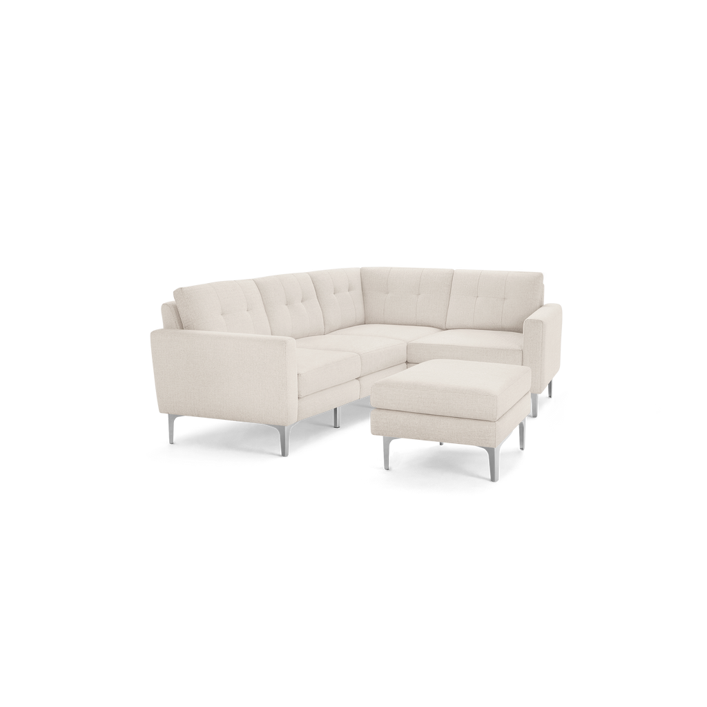 Beige fabric sectional sofa with tufted back cushions, angled armrests, metal legs, and matching ottoman.