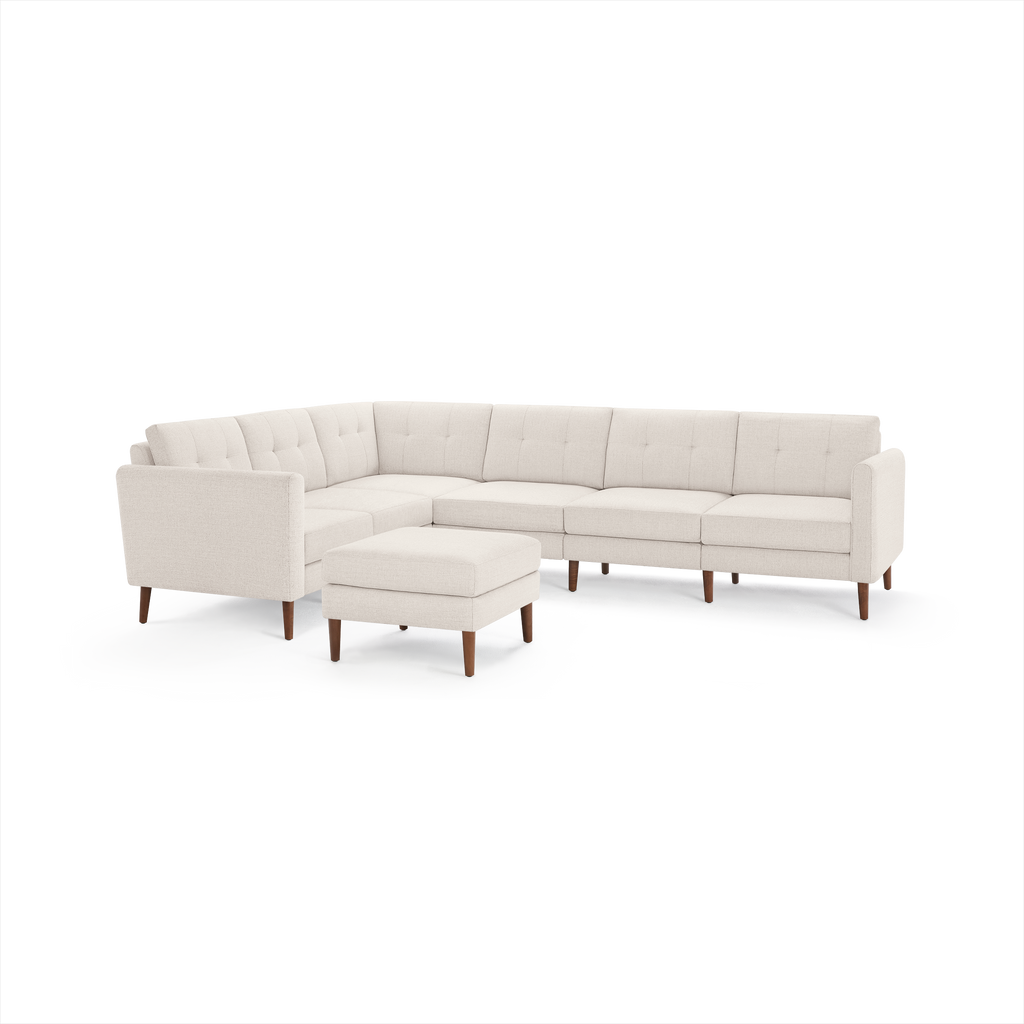 Beige L-shaped sectional sofa with tufted cushions, wooden legs, and matching square ottoman, modern mid-century design.