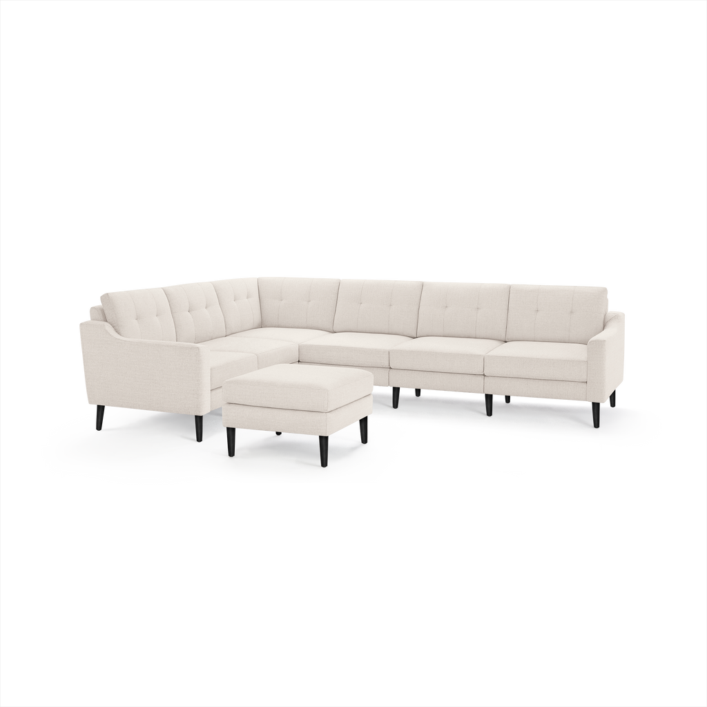 Light beige L-shaped sectional sofa with tufted back cushions and matching ottoman, featuring sleek black legs.