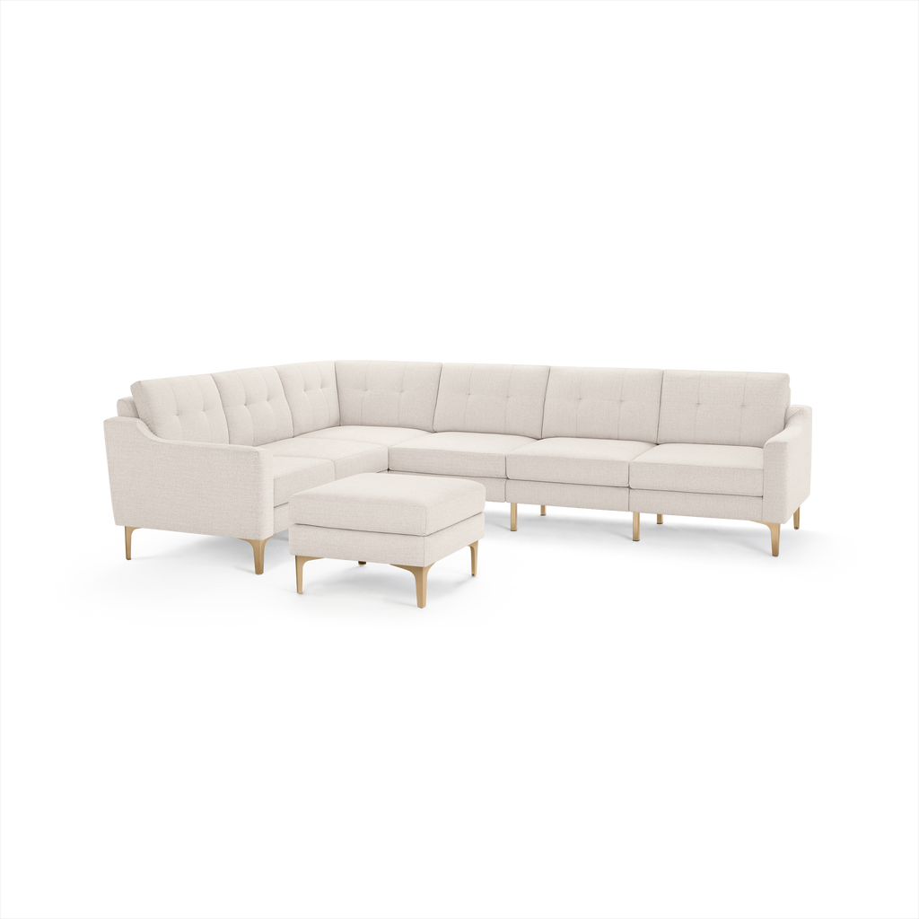 Cream-colored modern sectional sofa with tufted back cushions and matching ottoman, set on light wooden legs.