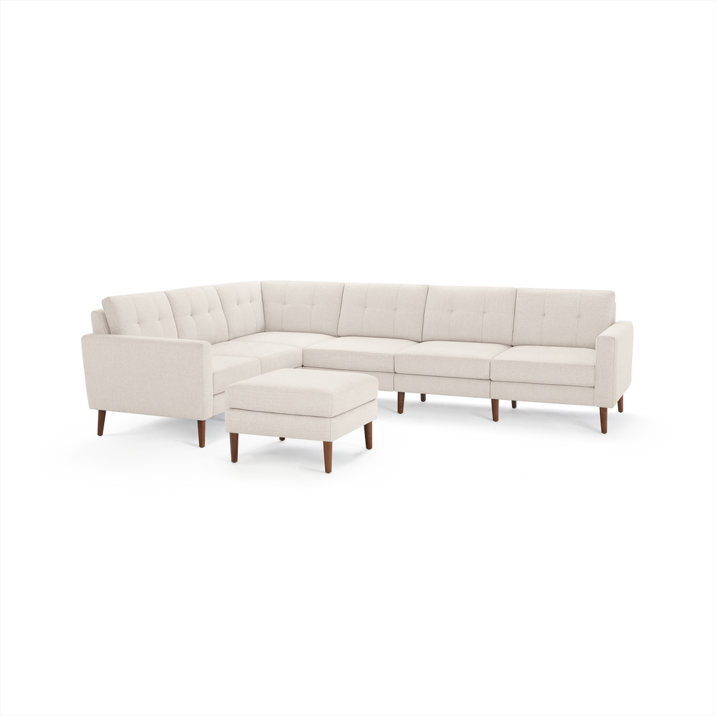 Cream-colored modern sectional sofa with tufted back cushions and wooden legs, accompanied by a matching square ottoman.