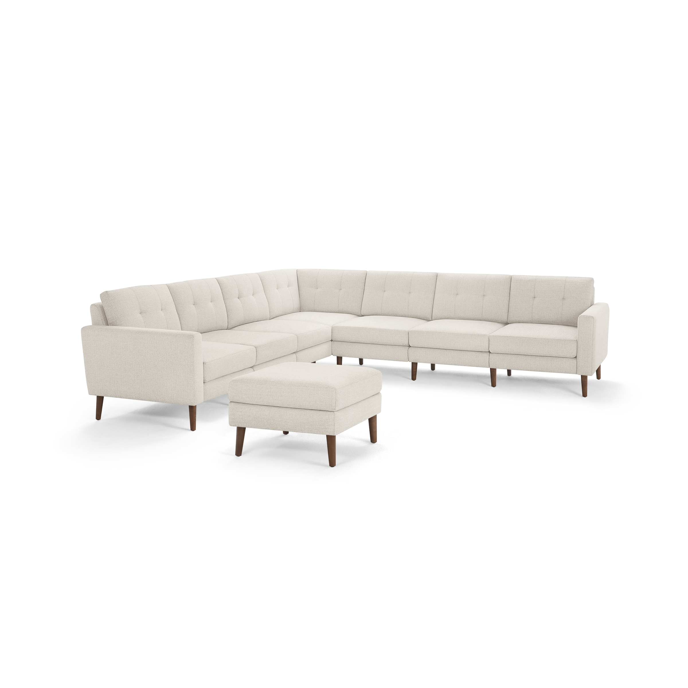 Modern beige L-shaped sectional sofa with tufted cushions and wooden legs, accompanied by a matching ottoman.