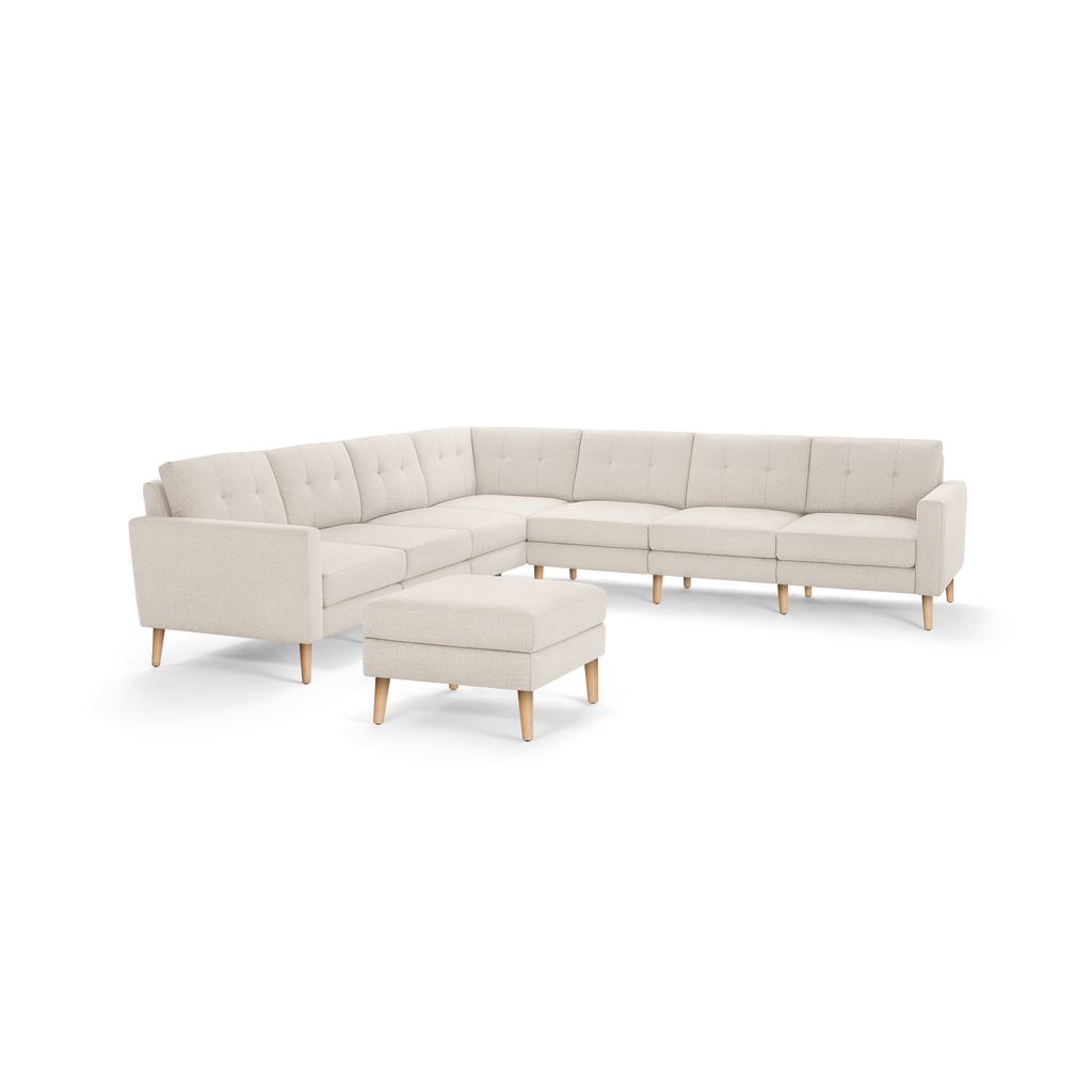 Beige L-shaped sectional sofa with tufted cushions, wooden legs, and matching ottoman, designed for modern living spaces.
