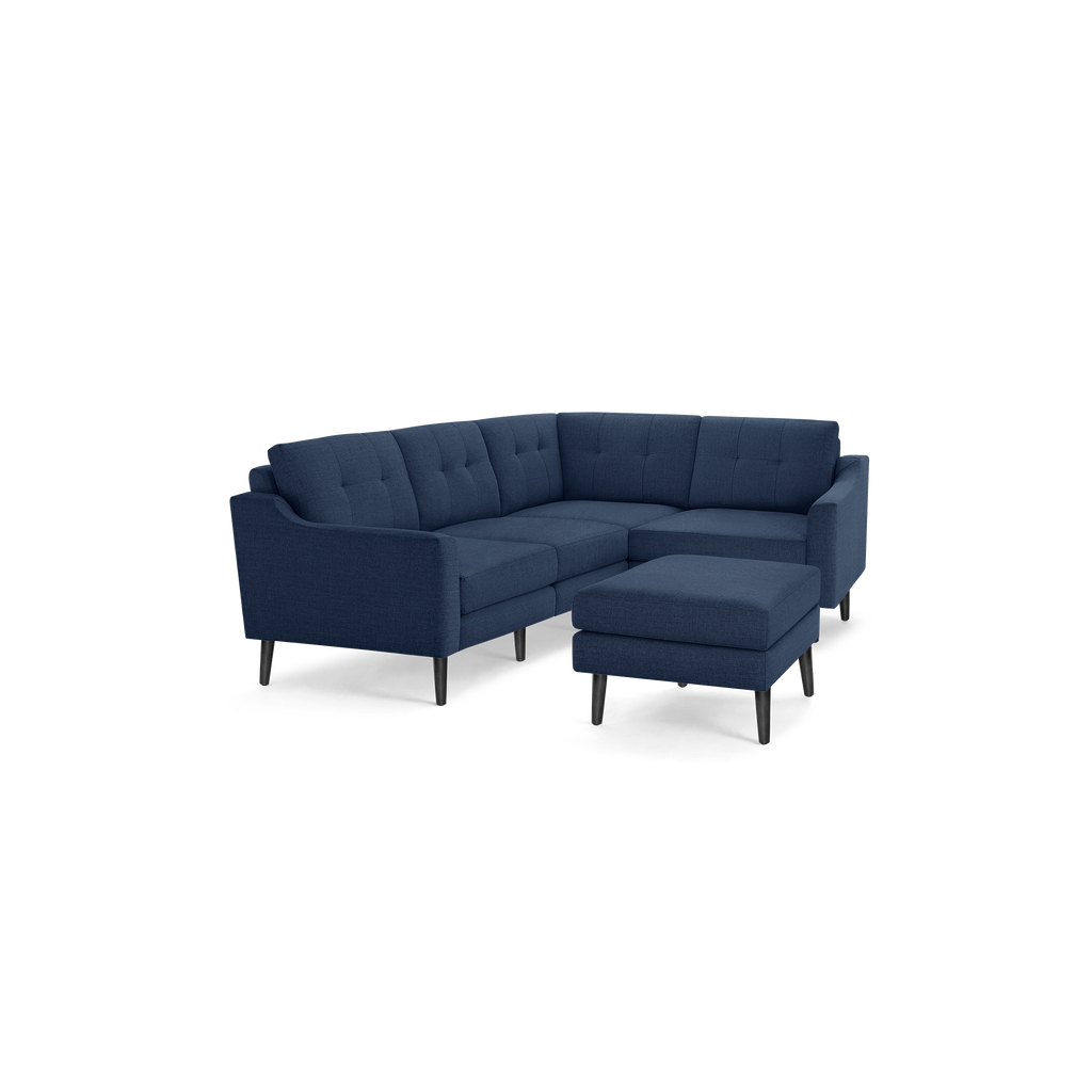 Modern L-shaped navy blue fabric sectional sofa with tufted cushions and matching ottoman on black legs.