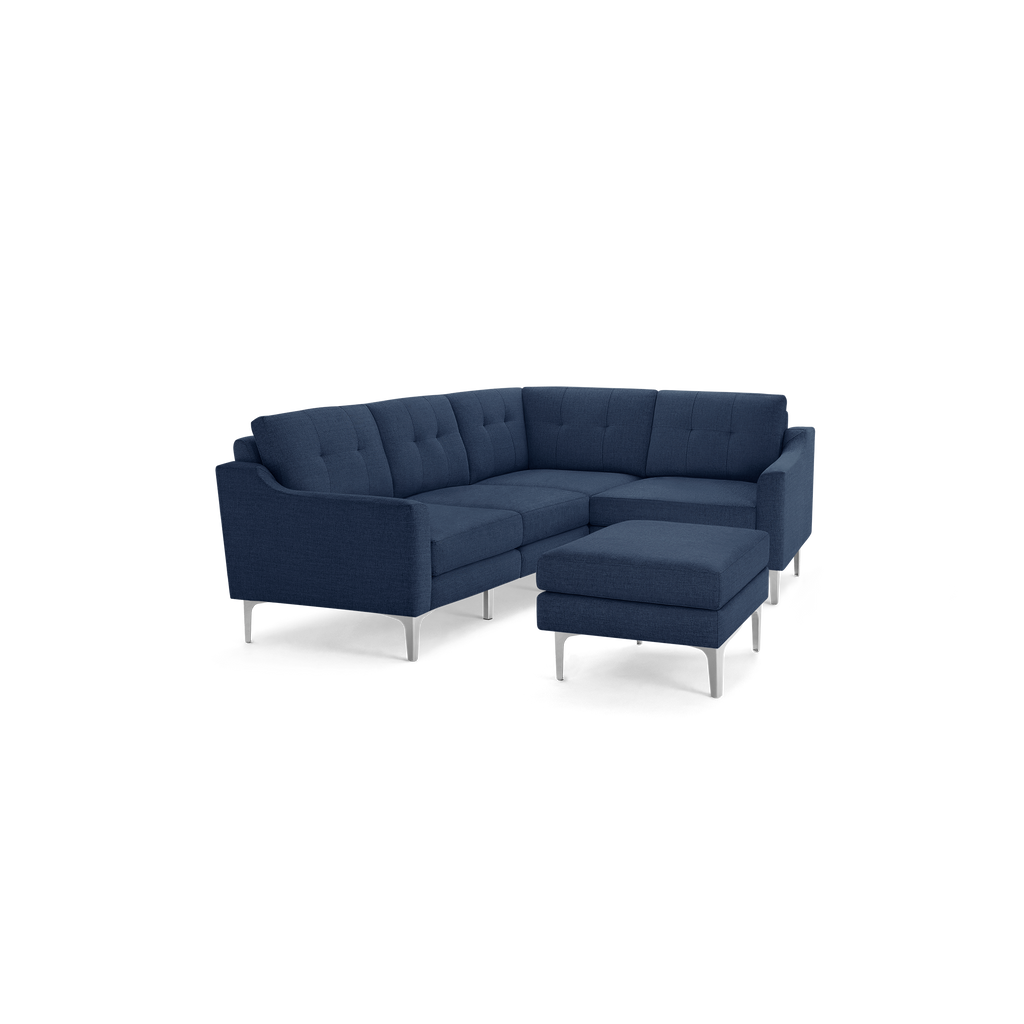 Modern navy blue fabric sectional sofa with tufted back cushions and matching rectangular ottoman on silver metal legs.