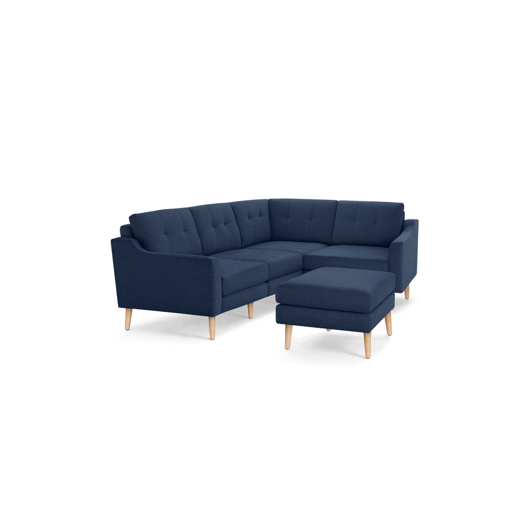 Modern navy blue fabric L-shaped sectional sofa with tufted back cushions and light wooden legs, includes matching ottoman.