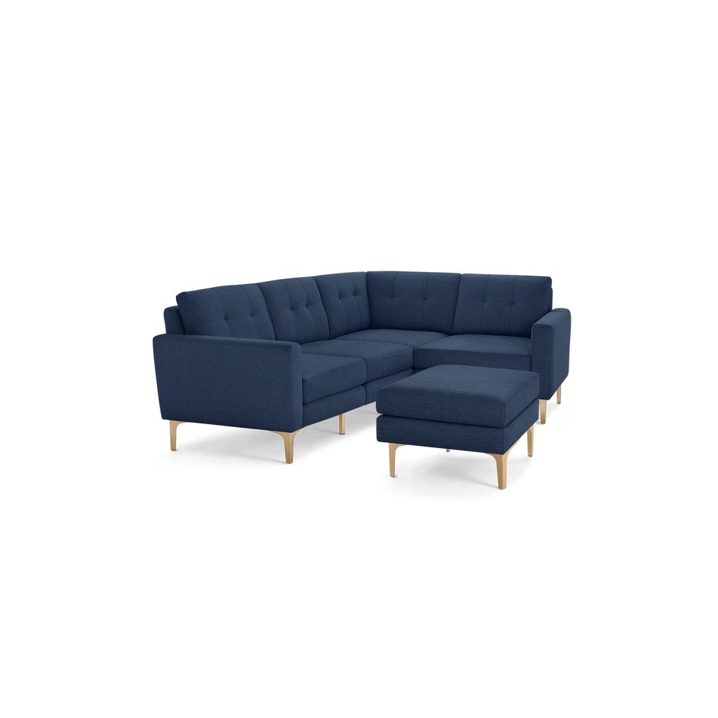 Dark blue fabric sectional sofa with tufted cushions and wooden legs, featuring a matching ottoman.