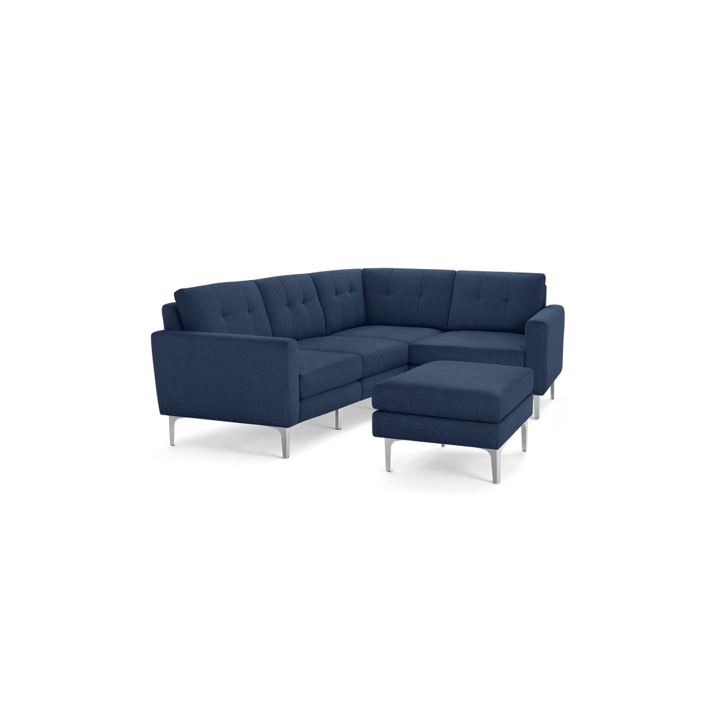 Modern navy blue sectional sofa with tufted cushions and matching ottoman, supported by sleek silver metal legs.