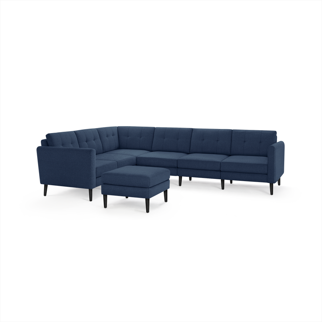 Modern navy blue L-shaped sectional sofa with tufted cushions and matching square ottoman, supported by black wooden legs.