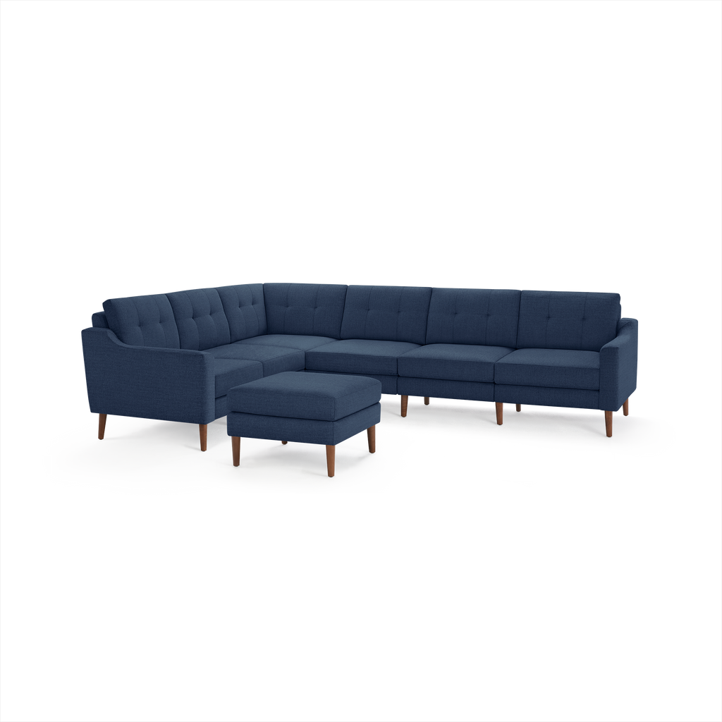 Mid-century modern navy blue fabric sectional sofa with tufted back cushions and wooden legs, including a matching ottoman.