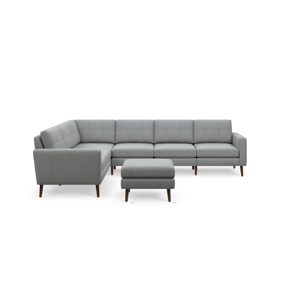 Light grey L-shaped sectional sofa with tufted cushions and wooden legs, accompanied by a matching ottoman.