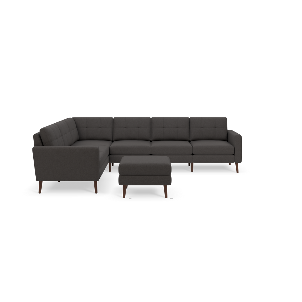 Dark gray L-shaped sectional sofa with tufted cushions and matching ottoman, supported by angled wooden legs.