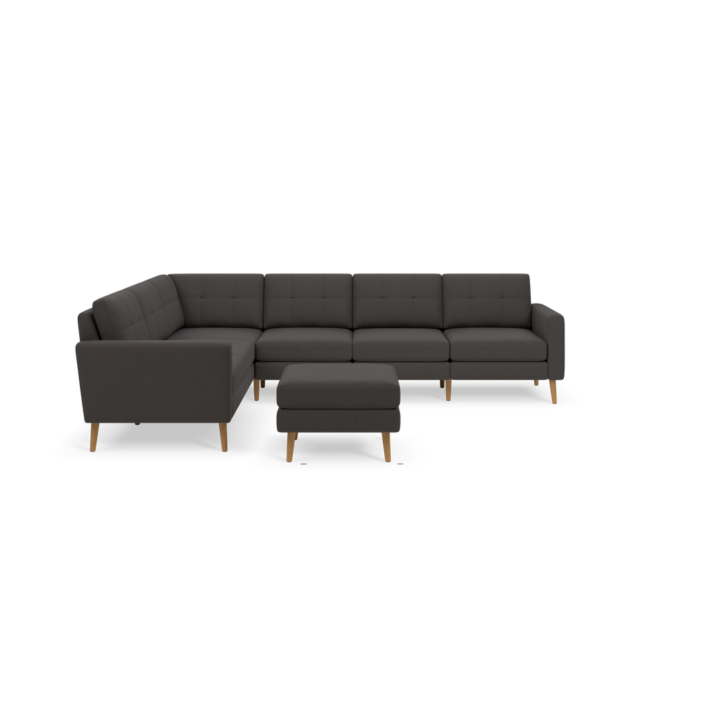 Modern dark gray L-shaped sectional sofa with tufted back cushions and matching ottoman, supported by wooden legs.