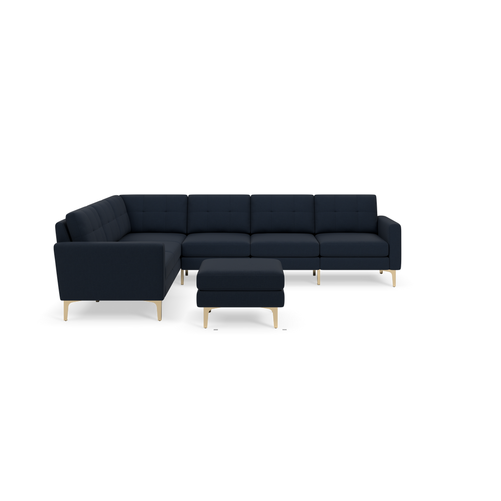 Modern L-shaped sectional sofa in dark blue fabric with matching ottoman and gold metal legs on black background.