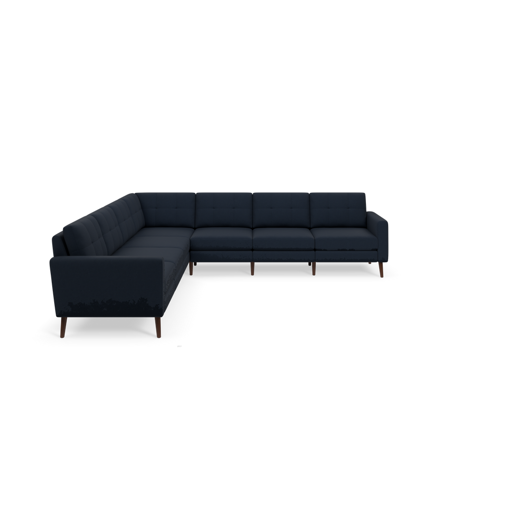 Dark blue L-shaped sectional sofa with tufted cushions, padded arms, and wooden legs on a black background.