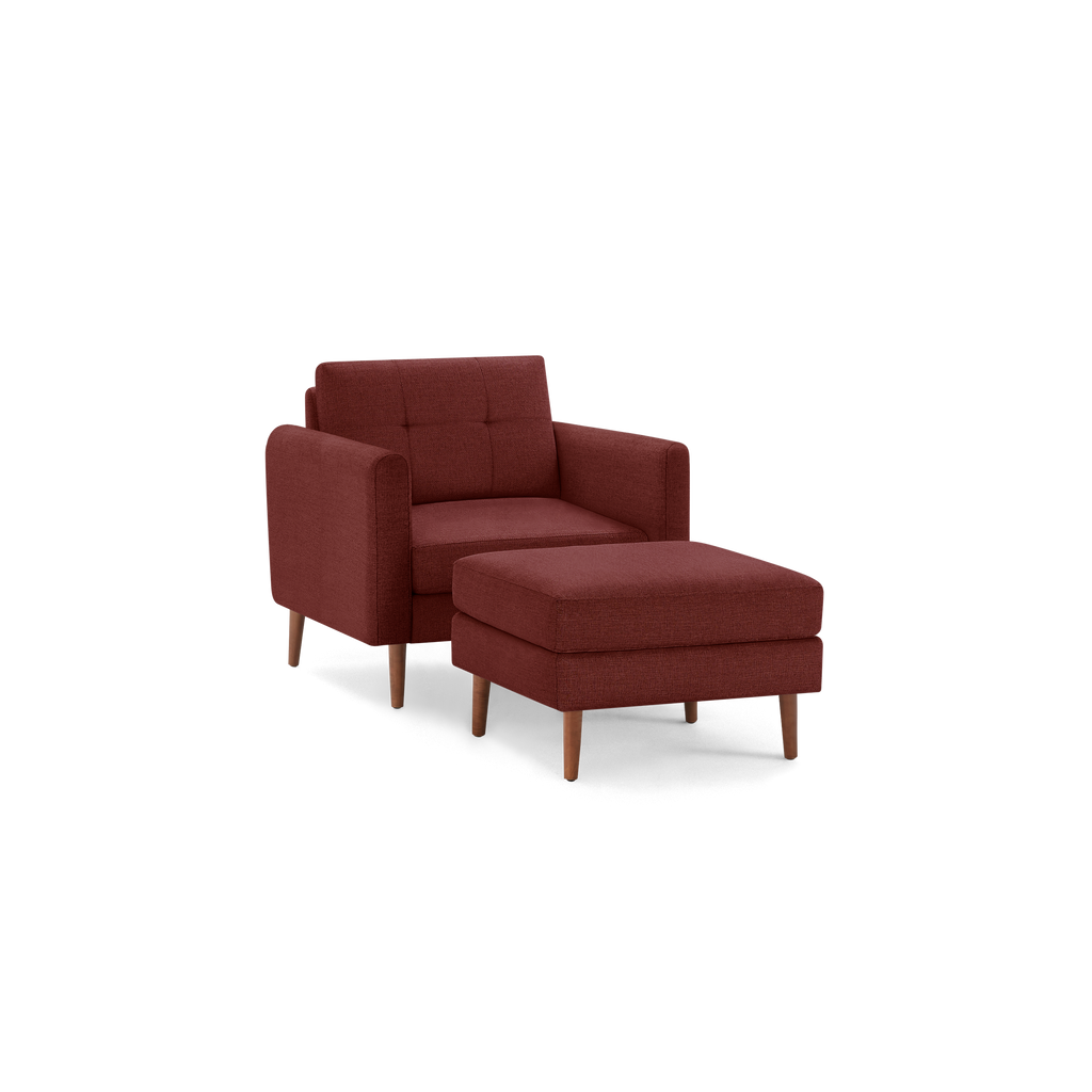 Mid-century style red fabric armchair with tufted backrest and matching cushioned ottoman on wooden legs.