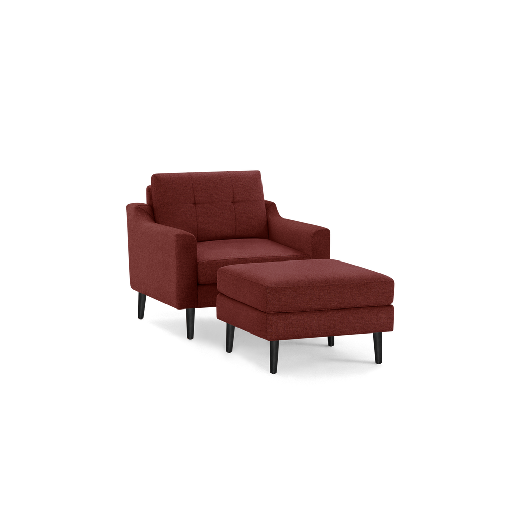 Contemporary brick-red upholstered armchair with matching ottoman, black tapered wooden legs, and tufted backrest cushion.