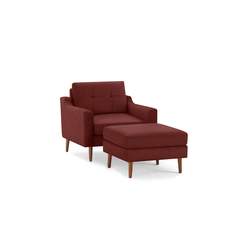 Mid-century style burgundy armchair with matching cushioned ottoman, both featuring wooden legs and tufted upholstery.