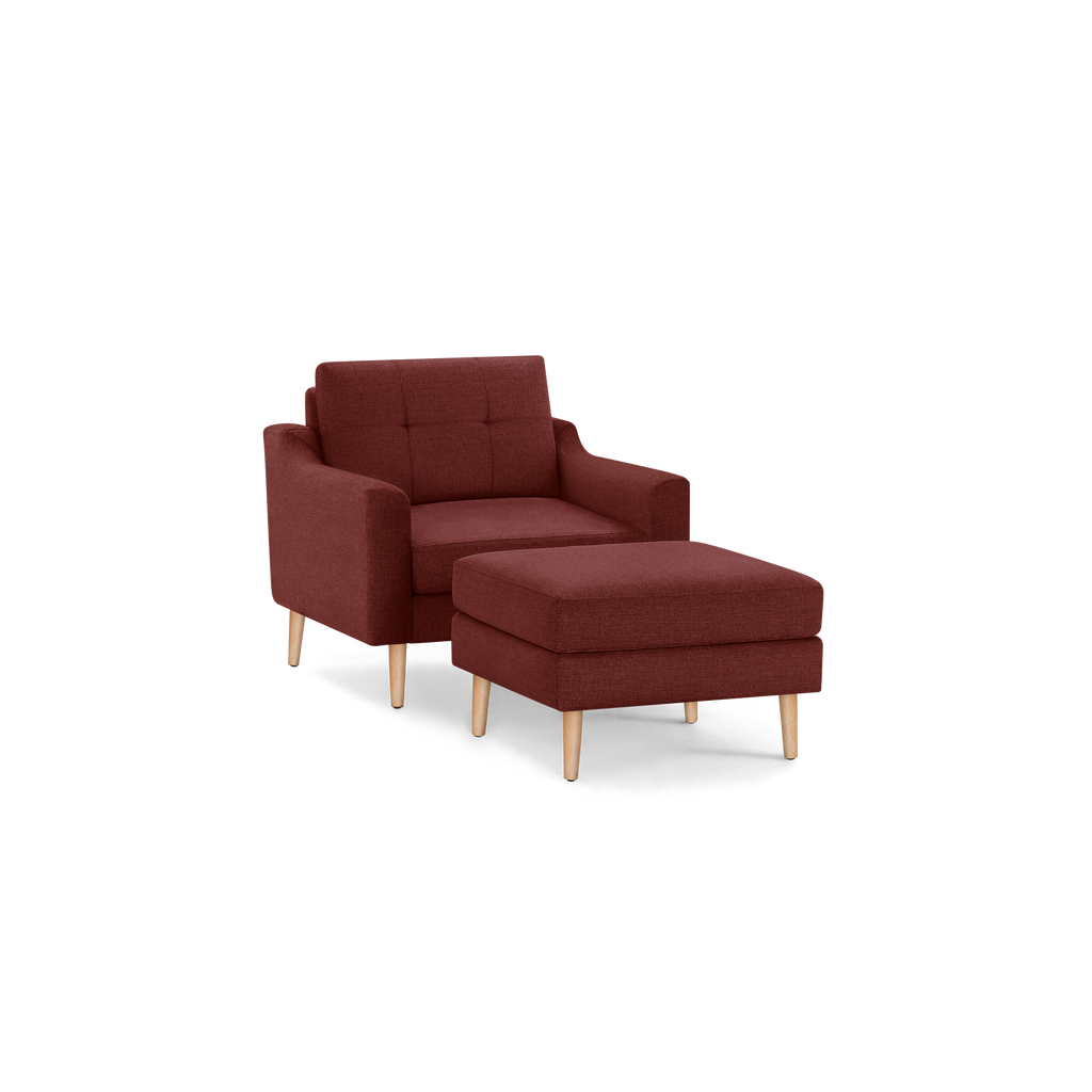 Modern mid-century style burgundy fabric armchair with matching cushioned ottoman, both featuring light wooden legs.