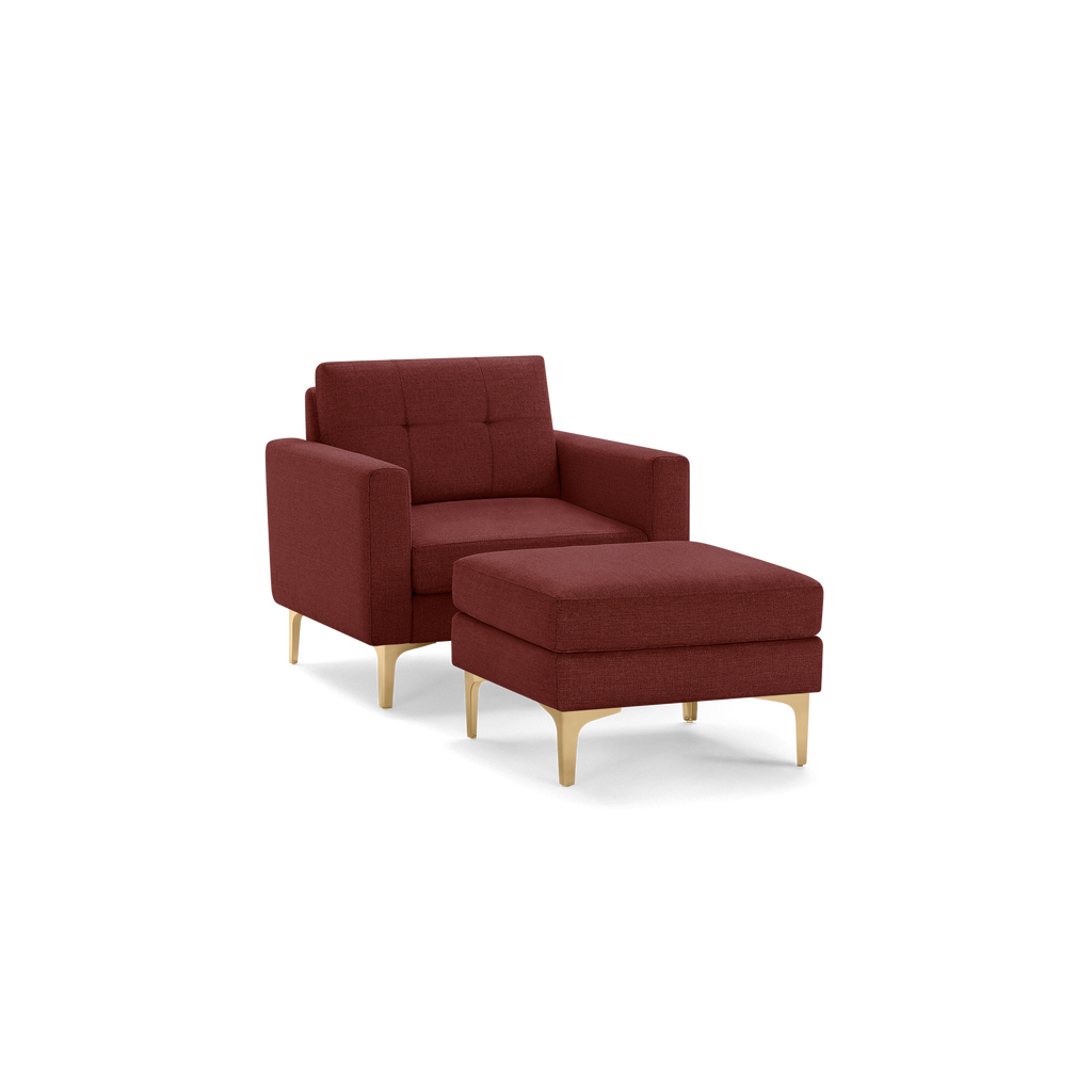 Modern burgundy fabric armchair with tufted backrest and matching cushioned ottoman, supported by light wooden legs.
