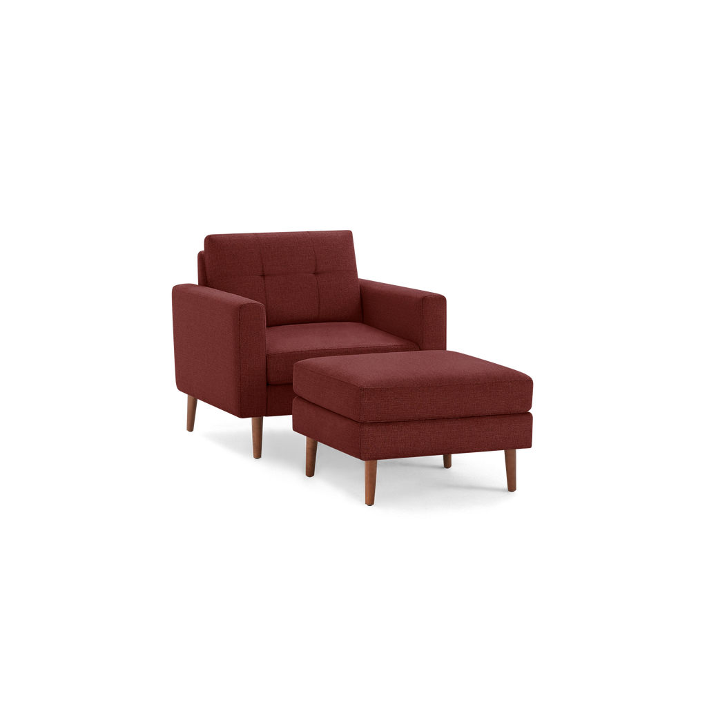 Mid-century modern deep red fabric armchair with matching ottoman, tufted backrest, and wooden tapered legs.