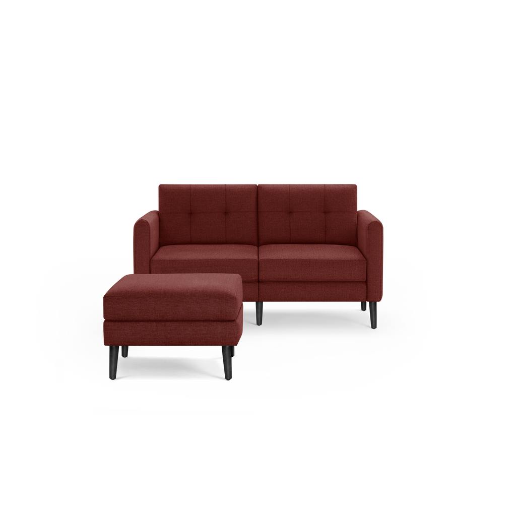 Modern two-seater sofa with matching ottoman in deep red fabric upholstery, featuring tufted cushions and black tapered legs.