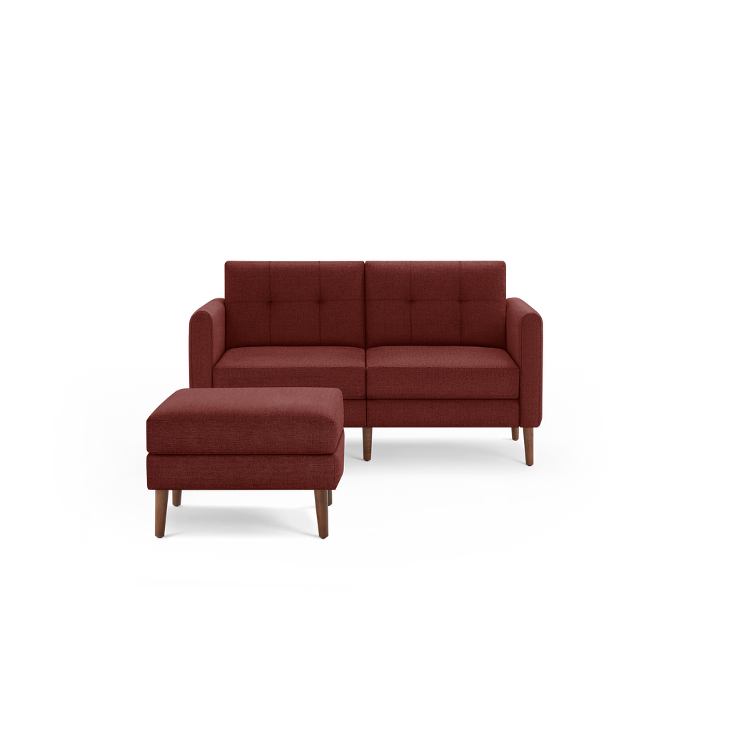 Mid-century style small red fabric loveseat with matching ottoman, featuring tufted cushions and wooden legs.