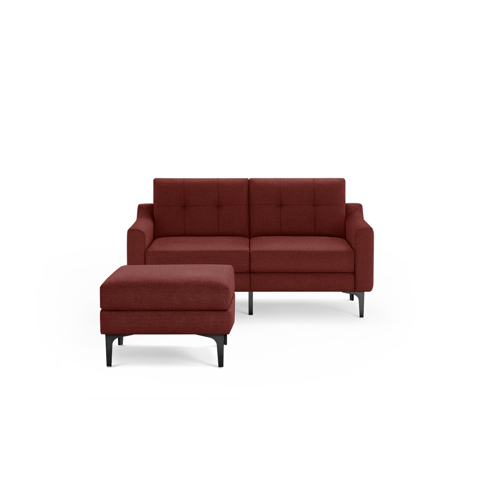 Modern two-seater sofa in deep red fabric with tufted backrest and matching ottoman, supported by black metal legs.
