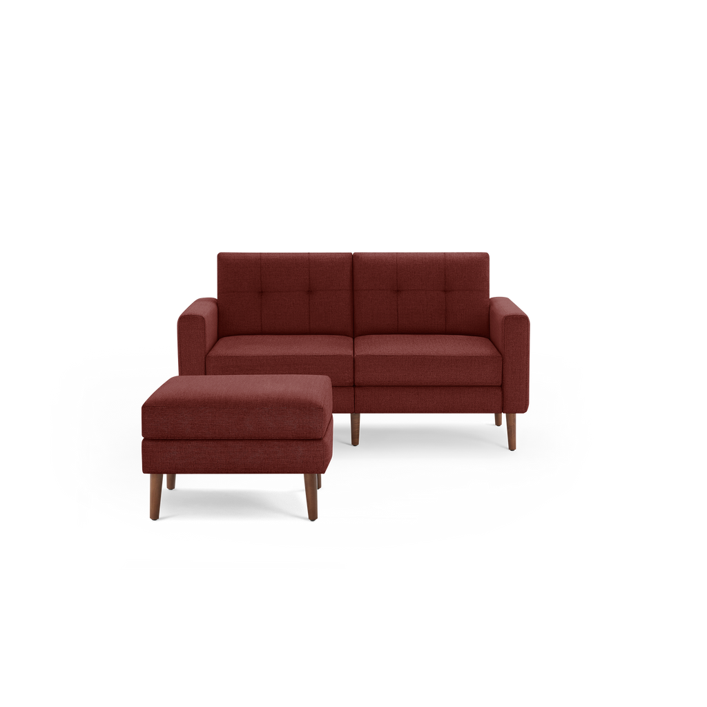 Mid-century style two-seater sofa and matching ottoman in rust-colored fabric with wooden legs and tufted back cushions.
