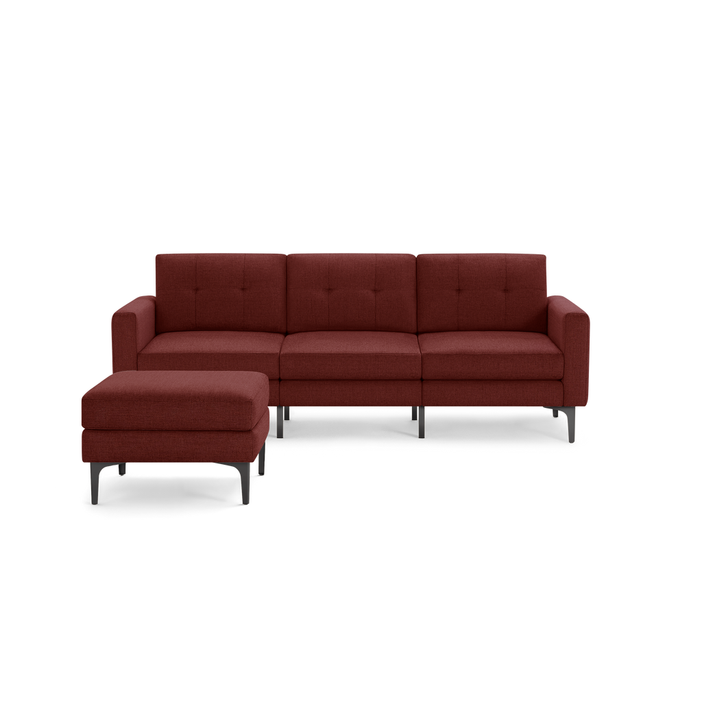 Modern three-seater sectional sofa in dark red upholstery with metal legs and matching ottoman, tufted back cushions.