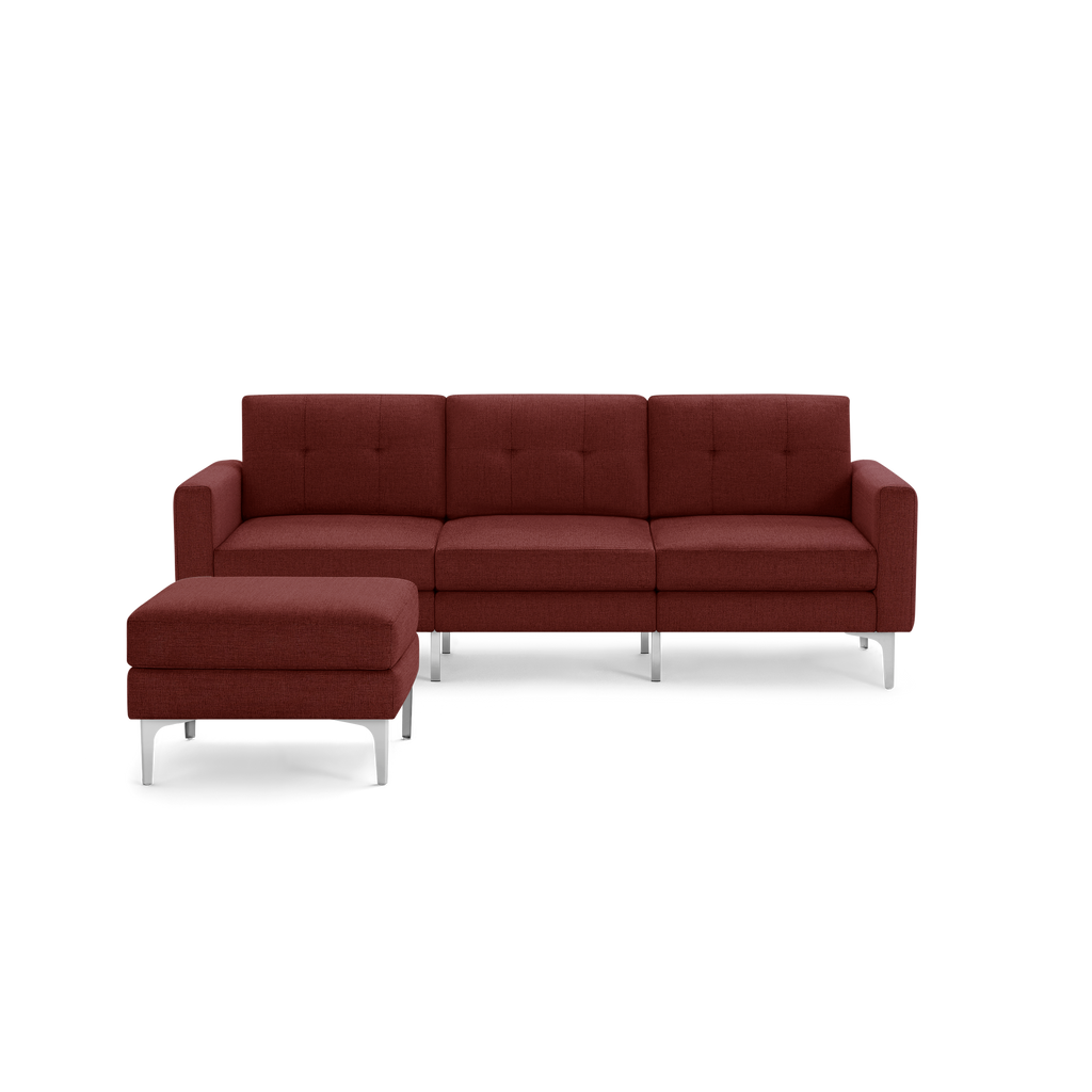 Modern sectional sofa in deep red fabric with tufted back cushions and sleek silver metal legs, featuring a matching ottoman.