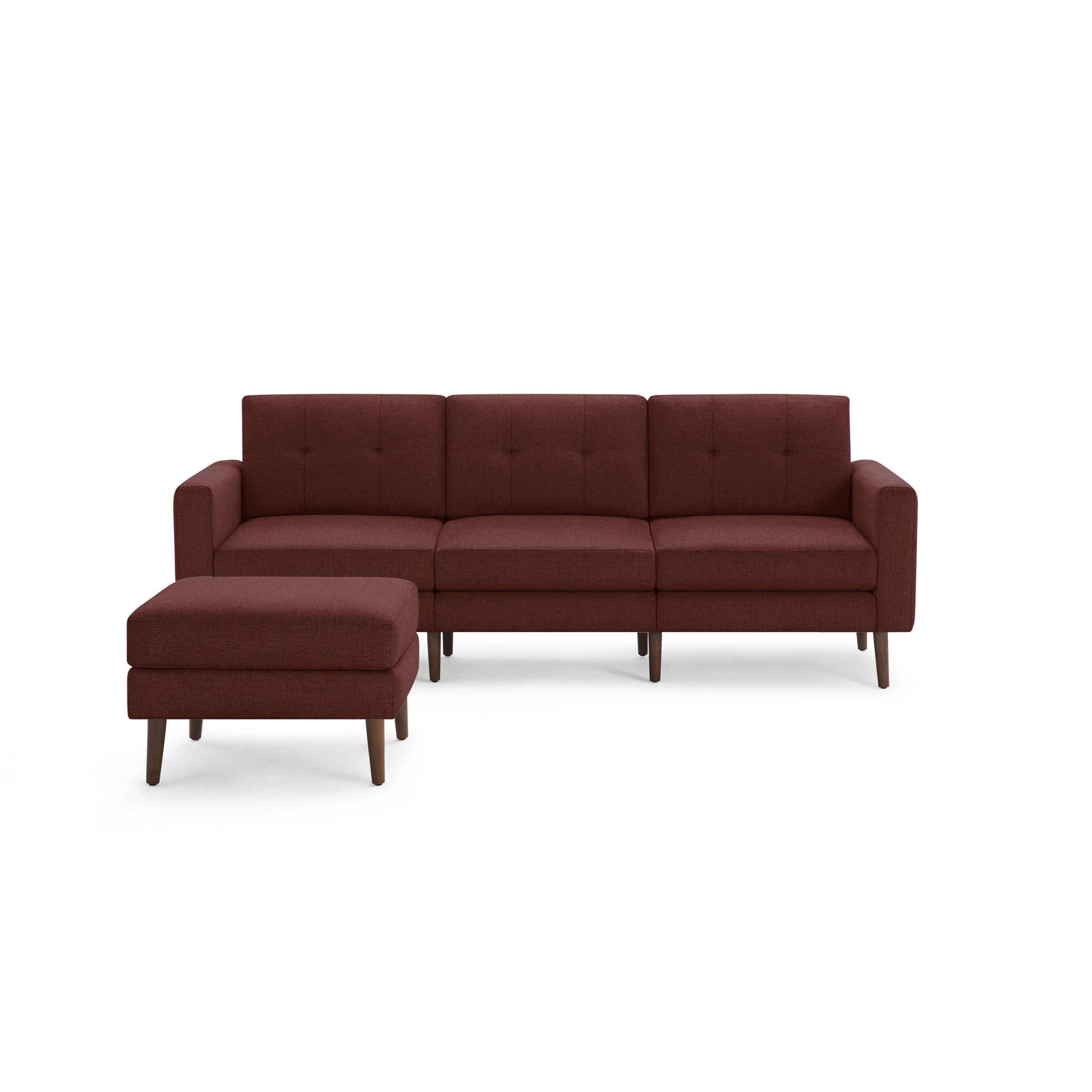Modern three-seater sofa with tufted cushions and matching ottoman in deep red fabric and wooden legs.