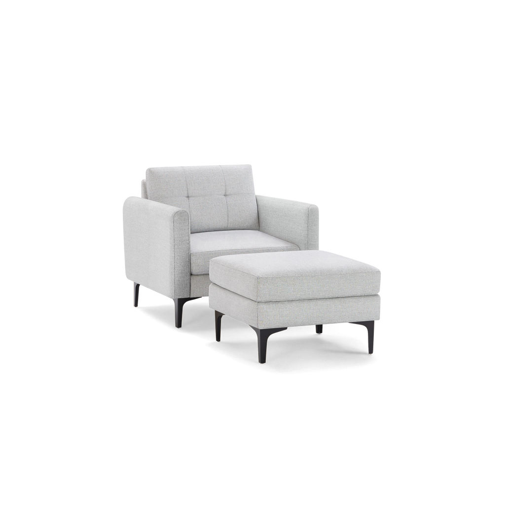 Light gray upholstered armchair with matching cushioned ottoman and black metal legs, featuring modern design and tufted backrest.