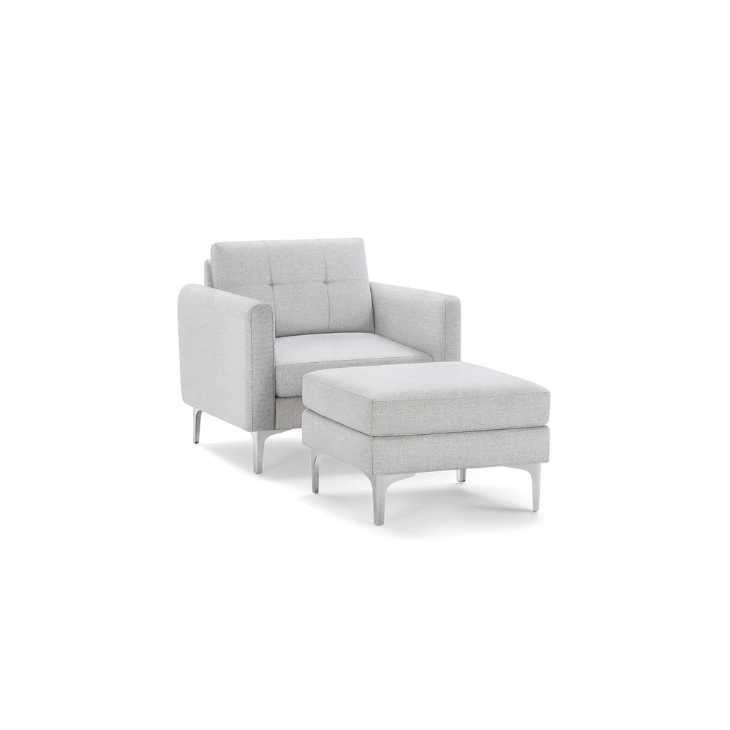 Light grey upholstered armchair with button-tufted backrest and matching cushioned ottoman, both featuring sleek metal legs.
