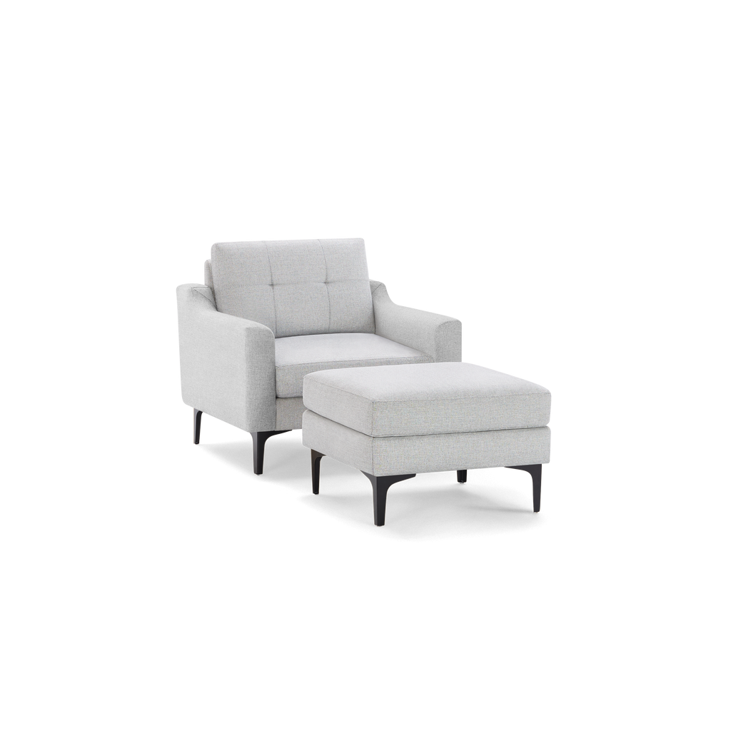 Modern light gray fabric armchair with matching cushioned ottoman, both featuring black tapered legs and clean, minimalist design.