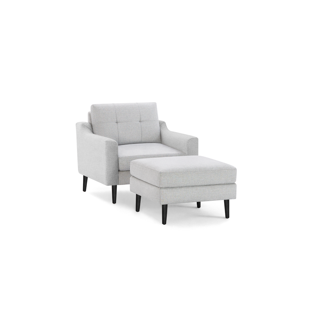 Light gray upholstered armchair with matching ottoman, dark wooden legs, and tufted backrest, contemporary design.