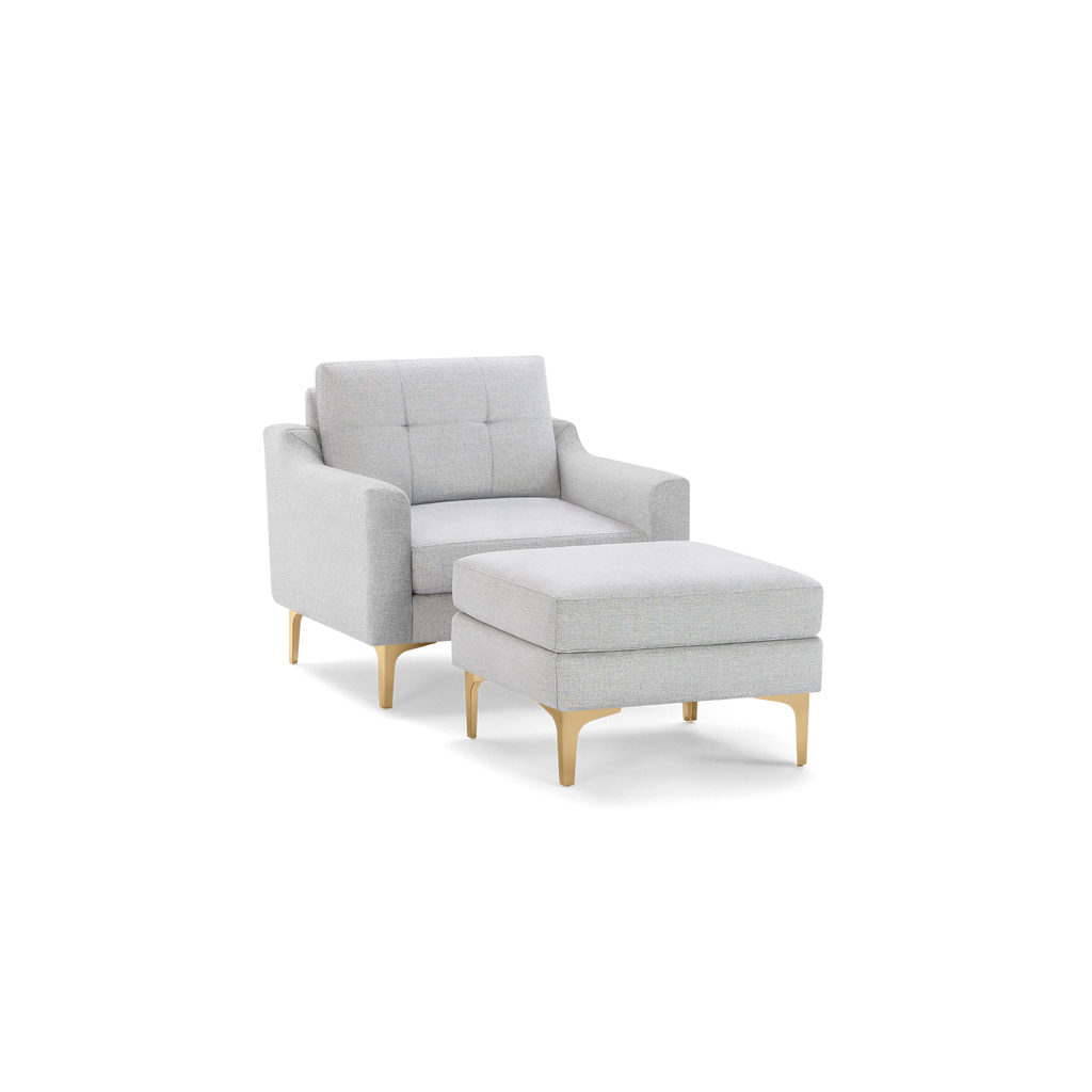 Light gray upholstered armchair with tufted backrest and matching ottoman, featuring wooden legs with a natural finish.
