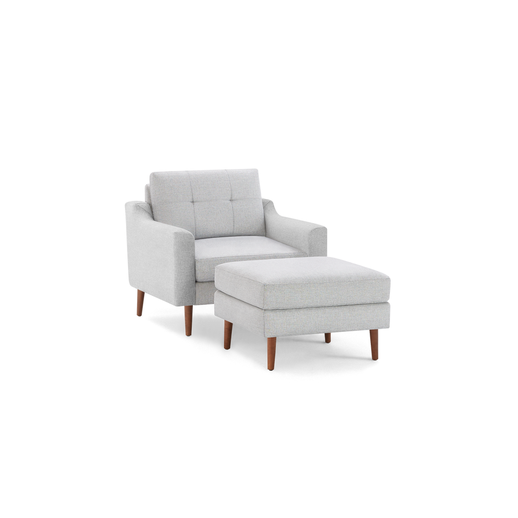 Light gray mid-century modern armchair with button-tufted backrest and matching cushioned ottoman, featuring wooden legs.