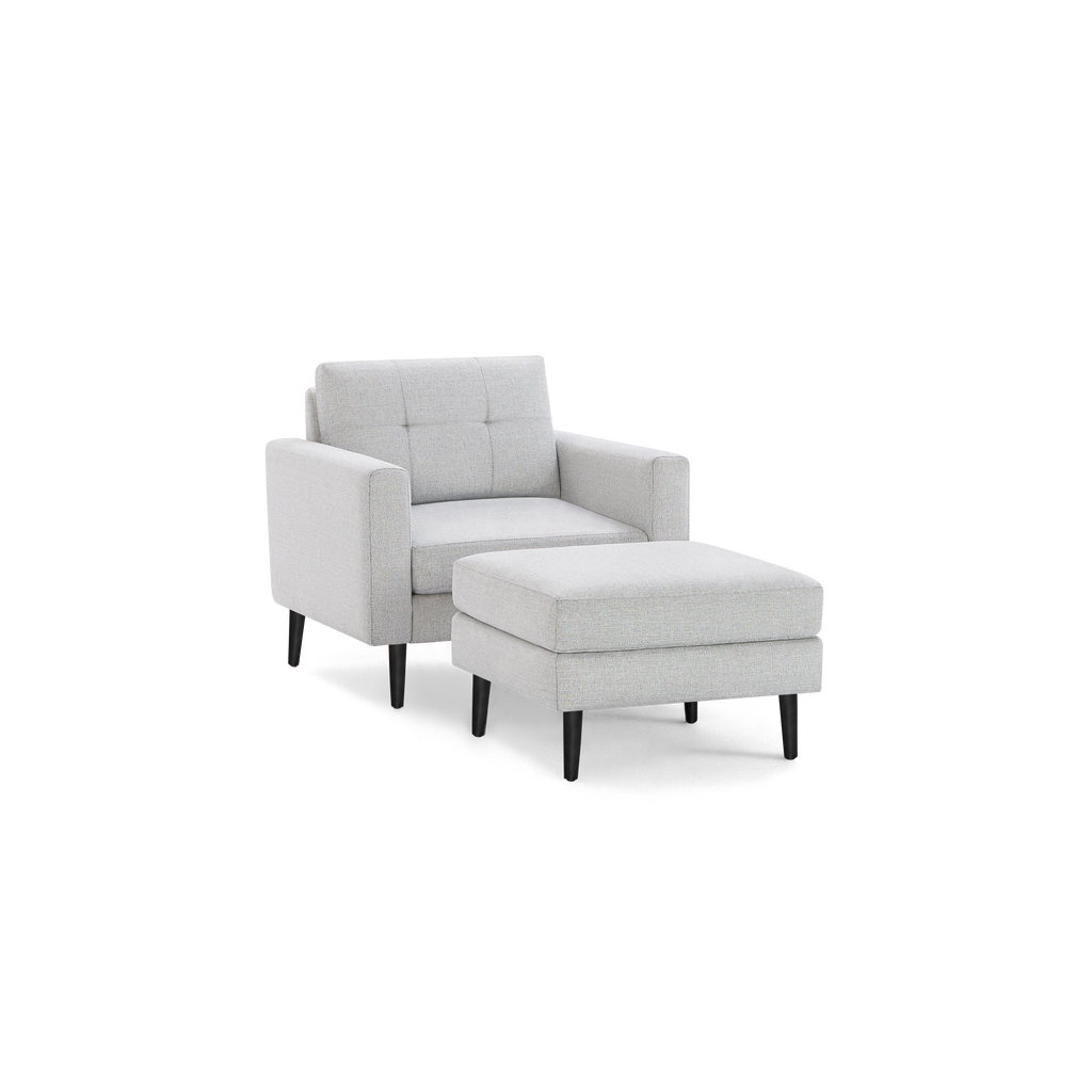 Light gray fabric armchair with matching cushioned ottoman, both featuring black tapered wooden legs.