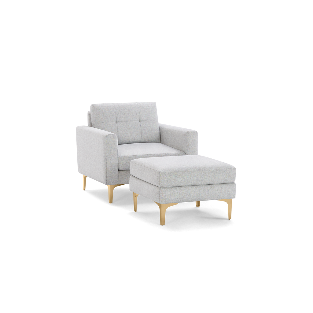 Light gray upholstered armchair with matching cushioned ottoman, tufted backrest, and slim golden legs, modern design.