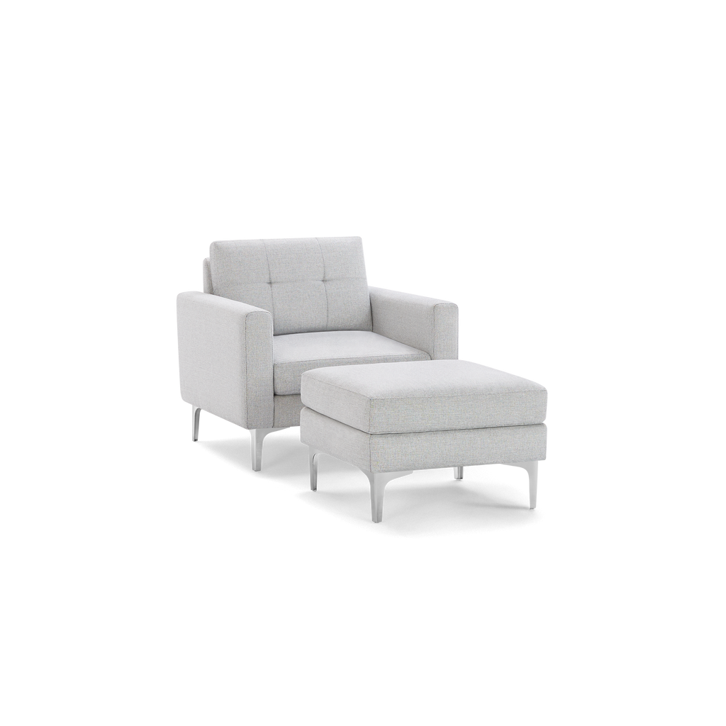Light gray upholstered armchair with tufted backrest and matching cushioned ottoman on sleek metallic legs.