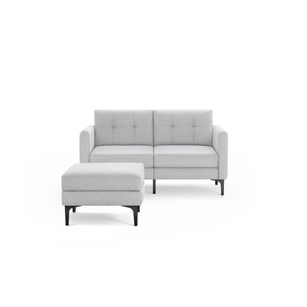 Light grey upholstered two-seater sofa with button-tufted back cushions and matching square ottoman on black legs.