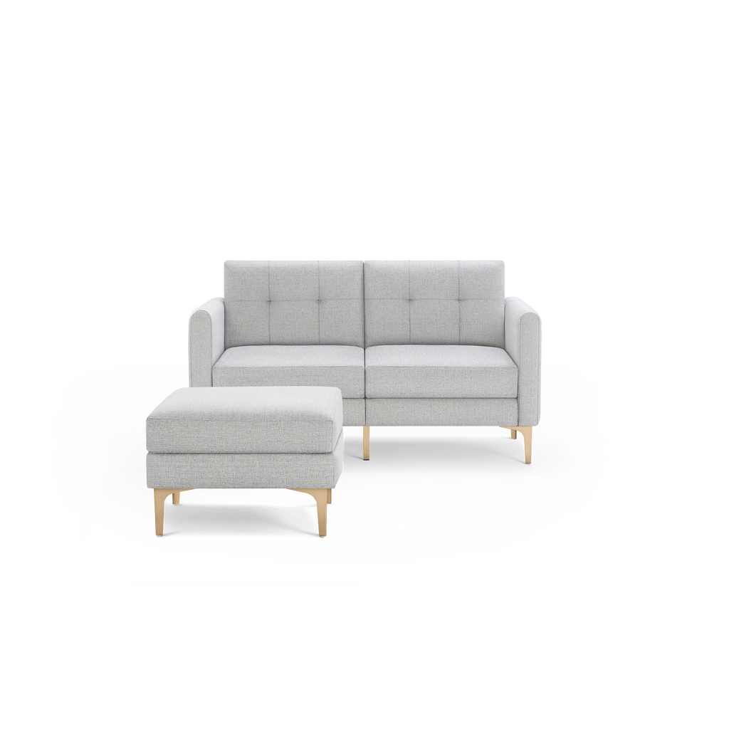 Light gray mid-century modern loveseat with tufted back cushions and matching ottoman, both featuring wooden legs.