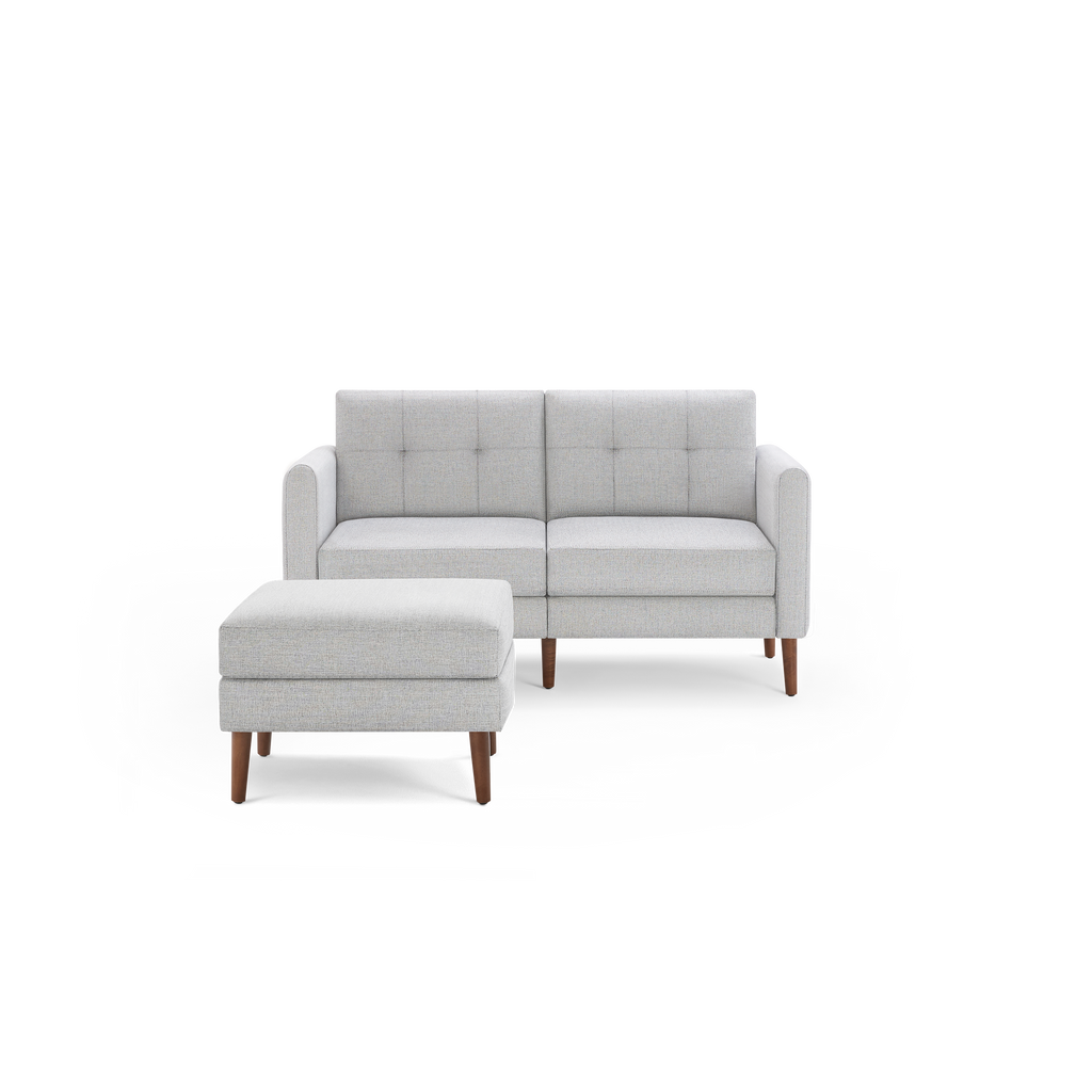 Light gray modern two-seater sofa with square tufted back cushions and a matching ottoman with wooden legs.