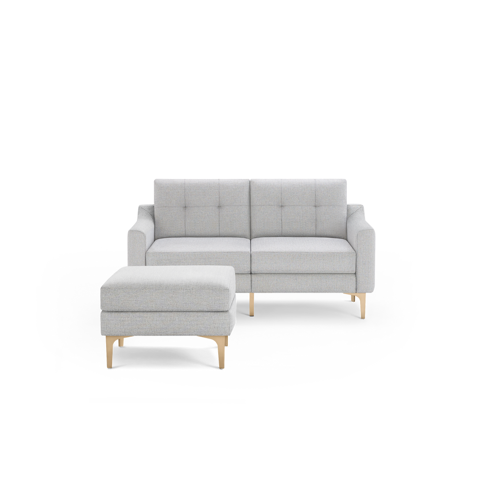 Light gray fabric loveseat sofa with tufted cushions paired with matching ottoman and wooden legs.