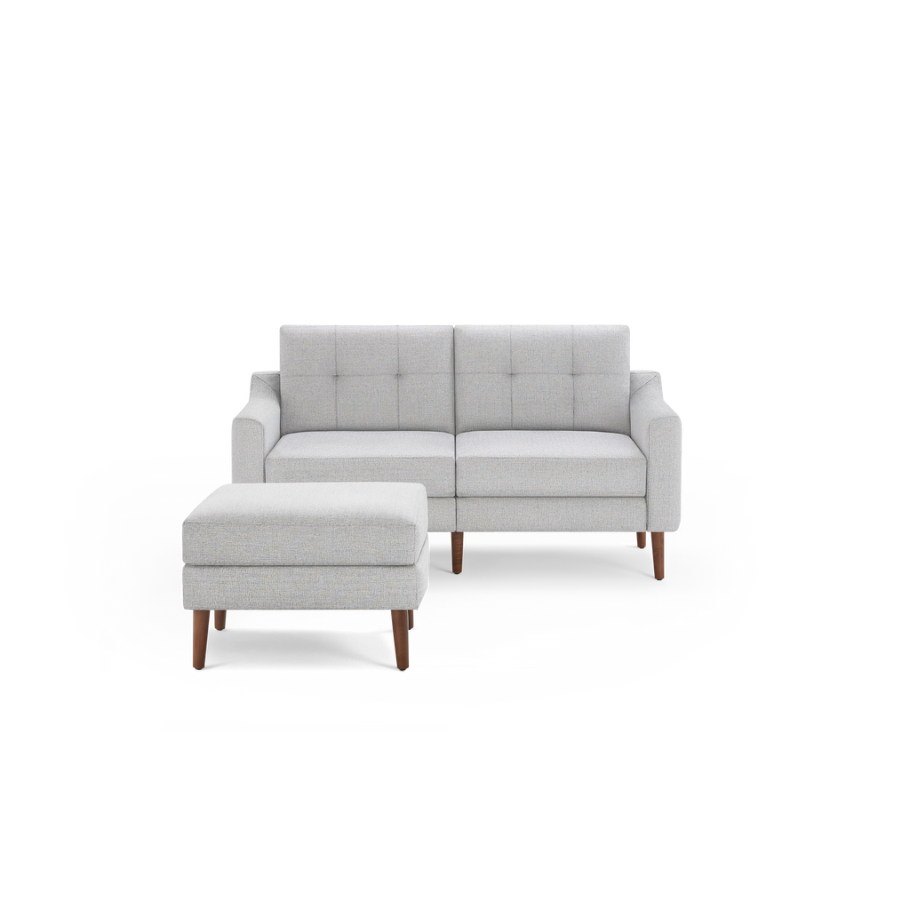 Light gray mid-century modern loveseat with tufted backrest and matching ottoman on wooden legs, isolated on black background.