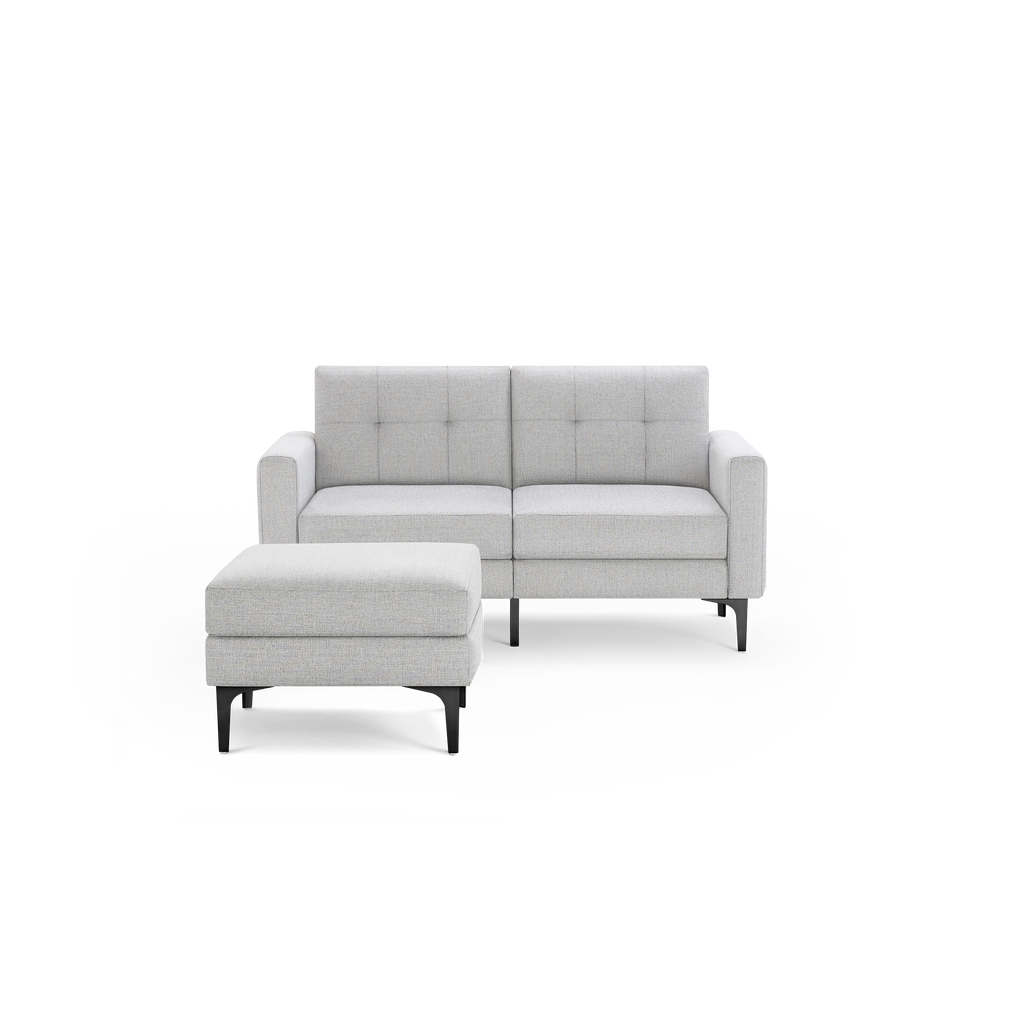 Light gray upholstered two-seater sofa with matching ottoman, featuring tufted cushions and black metal legs.