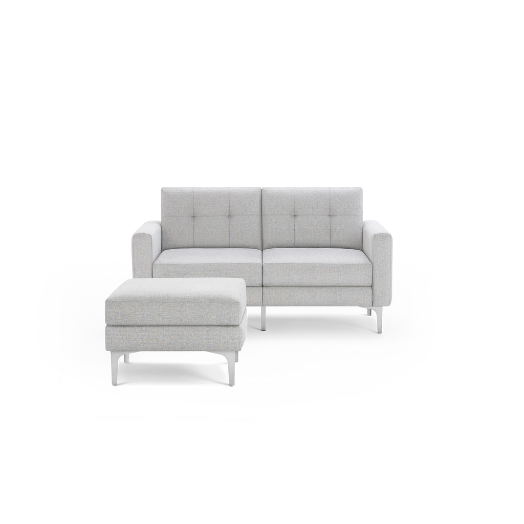 Light gray upholstered two-seater sofa with matching ottoman, square armrests, tufted back cushions, and slender metal legs.