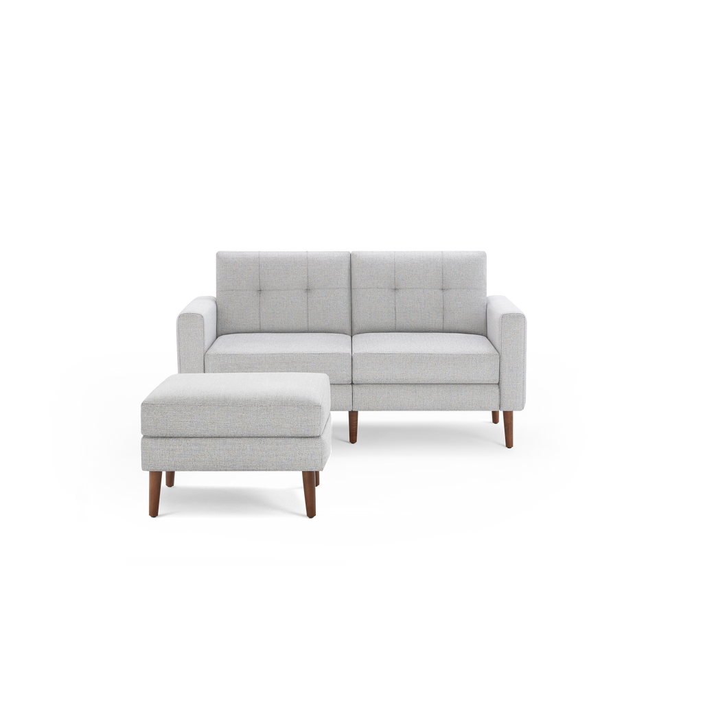 Light gray modern two-seater sofa with tufted back cushions and matching ottoman, featuring wooden tapered legs.