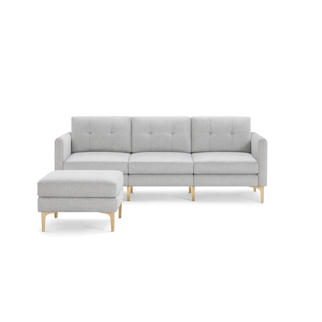 Light gray modern sectional sofa with tufted back cushions, wooden angled legs, and matching ottoman on left side.